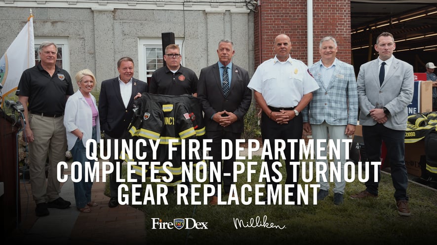 Quincy Fire Department representatives standing in front of brick building holding Fire-Dex turnout gear.