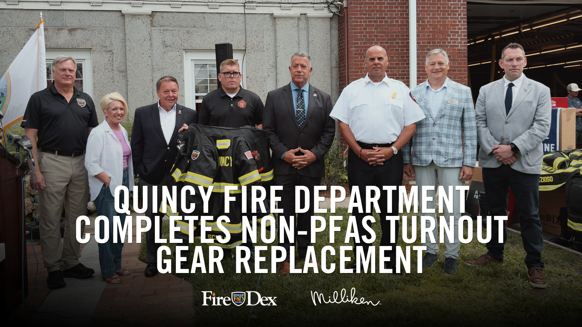 Quincy Fire Department representatives standing in front of brick building holding Fire-Dex turnout gear.