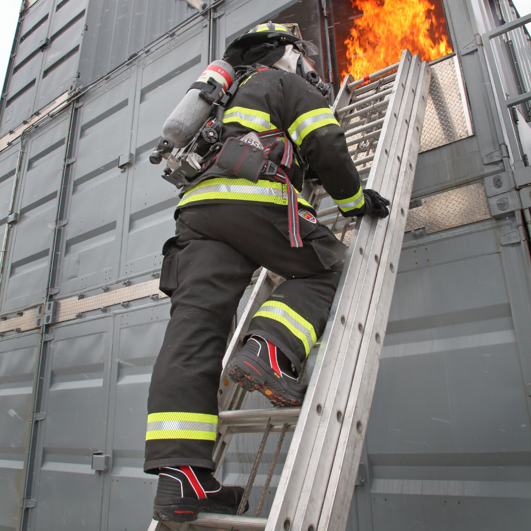 Firefighter climbing a ladder to a fire. 